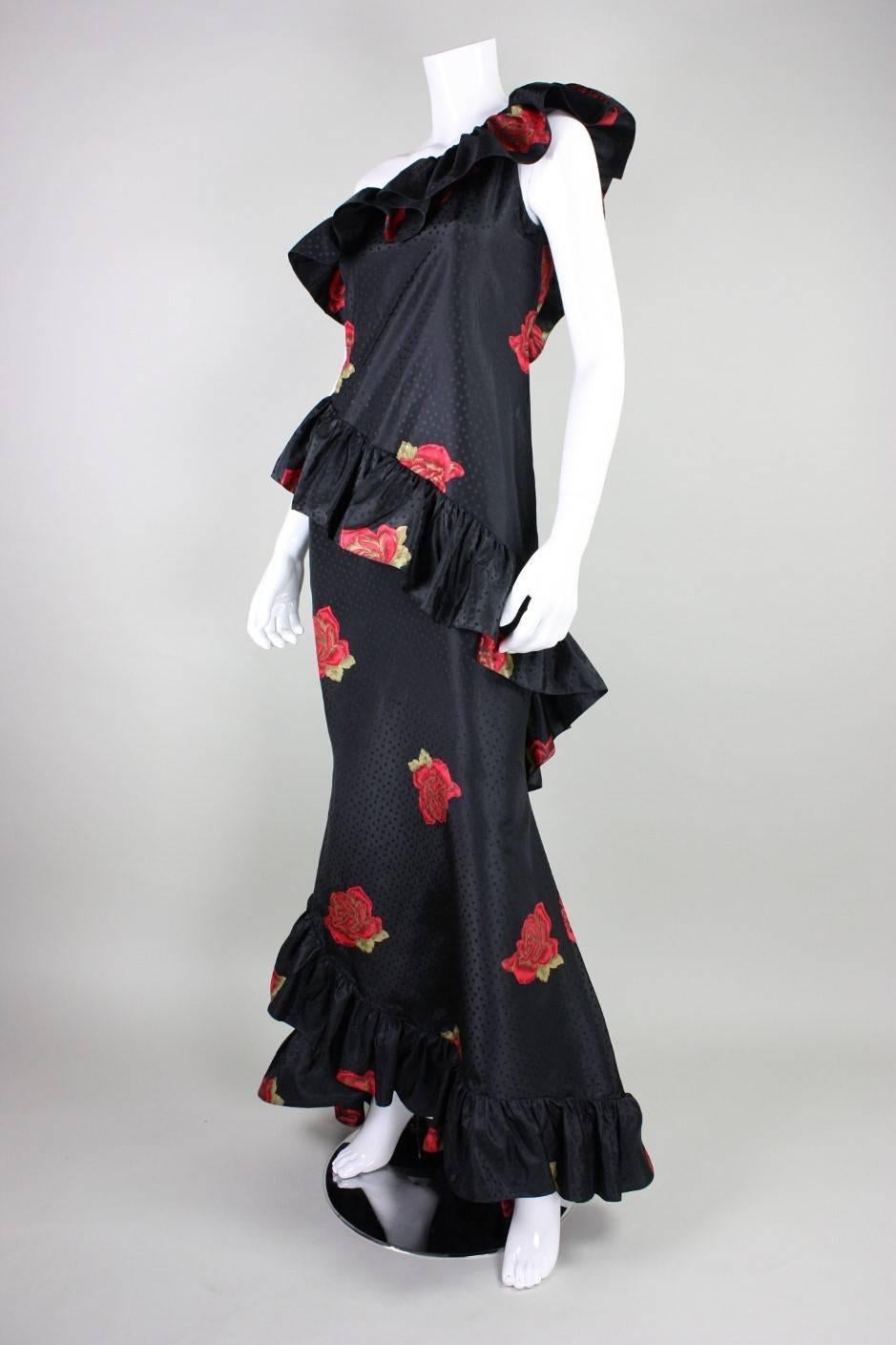 Vintage gown likely dates to the 1980's and is made of black silk with a floral print.  Wide ruffles encircle the gown and trim along the bust and hemline.  Gown is 5