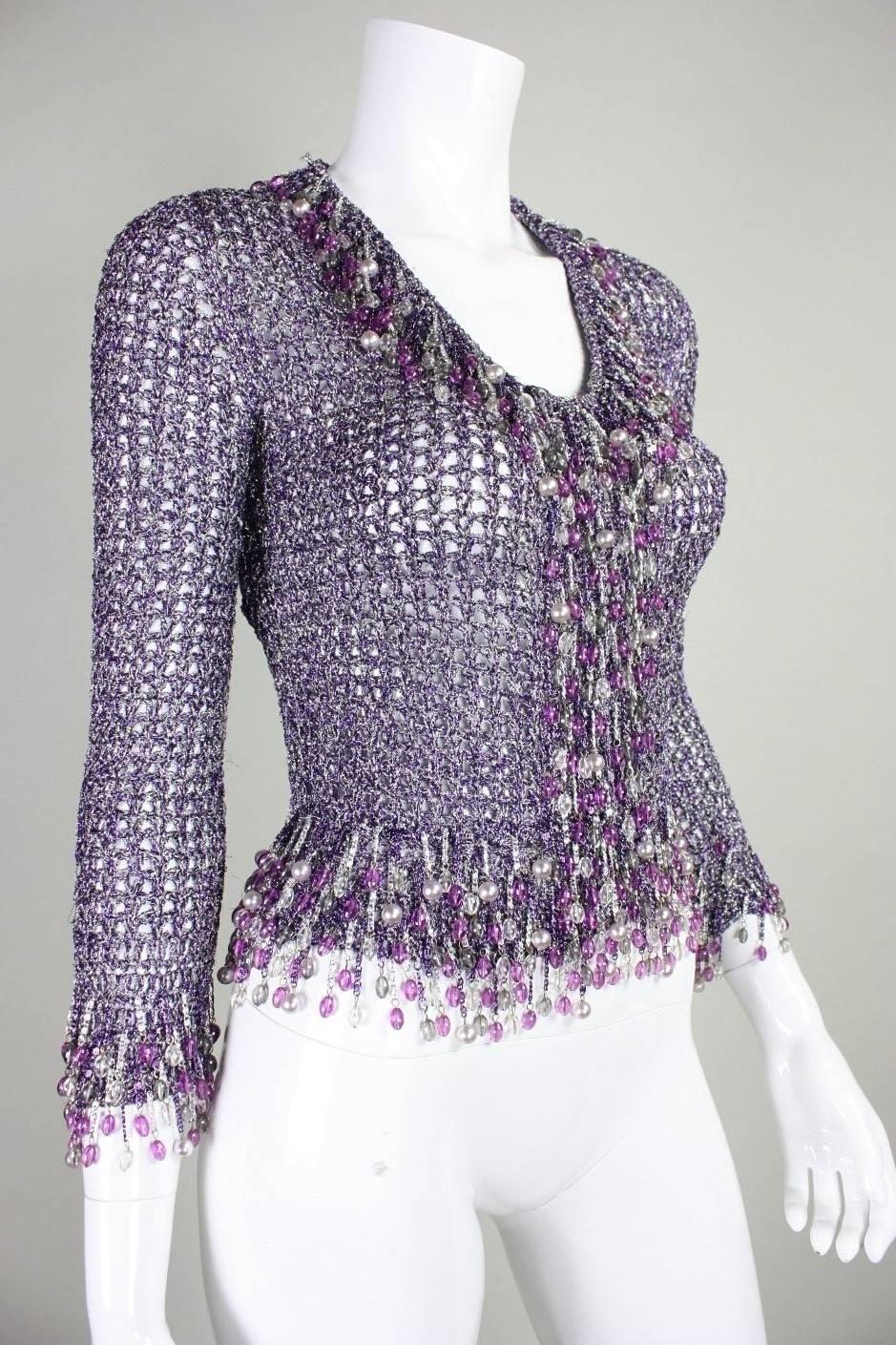 Loris Azzaro silver and purple metallic sweater has chain and beaded trim around neckline, hem, cuffs, and center front.  Center front snap closure.  Unlined.

No size label, but we estimate that it is best suited for a modern day XS.