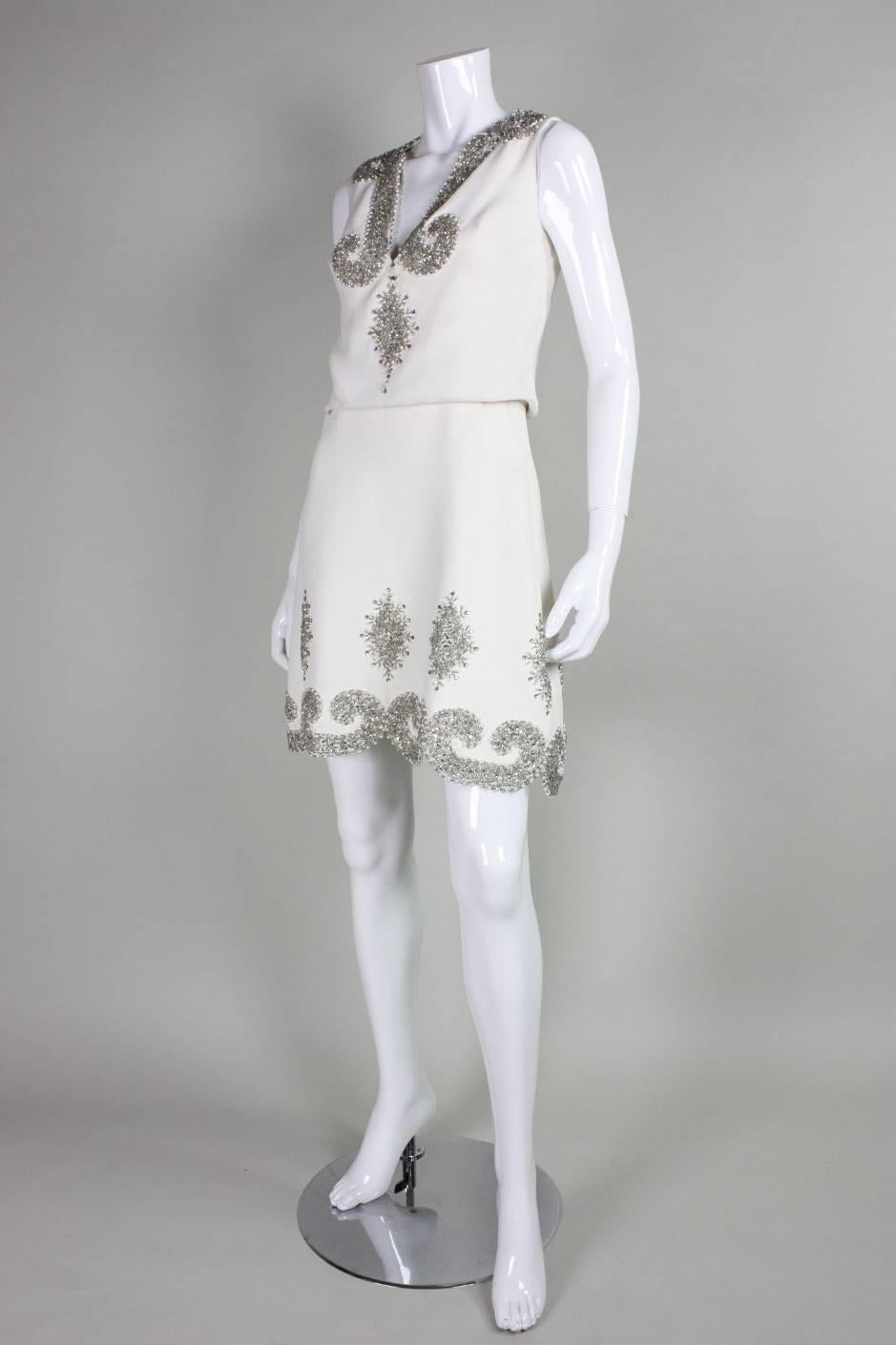 Vintage party dress from Italian boutique Renata dates to the 1960's.  It is made of white crepe with beautiful silver-toned rhinestone and beaded trim and detailing.  Scalloped hem.  Fully lined. Center back zipper.

No size label, but it would