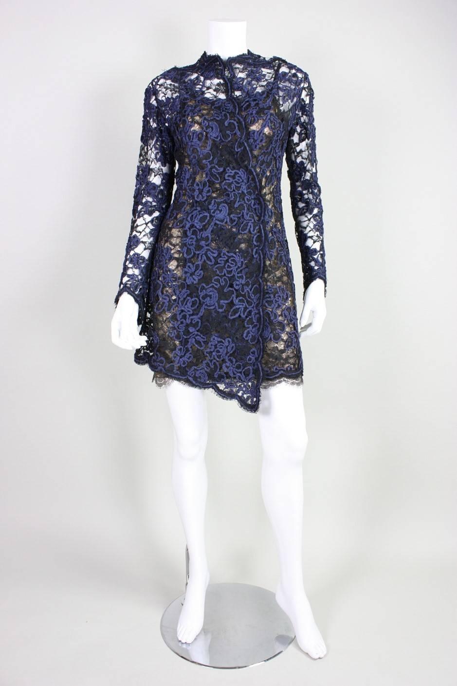 Vintage ensemble from Geoffrey Beene dates to the 1990's and consists of a lace dress and coat.  Metallic gold lace mini dress has spaghetti straps, scalloped hem, and a center back zipper. Black lace overcoat has navy ribbon over-embroidery in a