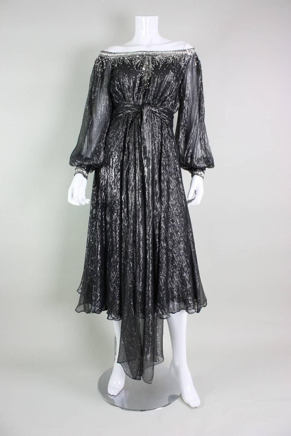 Vintage party dress from Nolan Miller dates to the 1970's through early 1980's. It is made of black chiffon with a silver lurex pinstripe. Neckline is off the shoulders and trimmed with sequins, bugle beads, and square rhinestones.  Flame-like