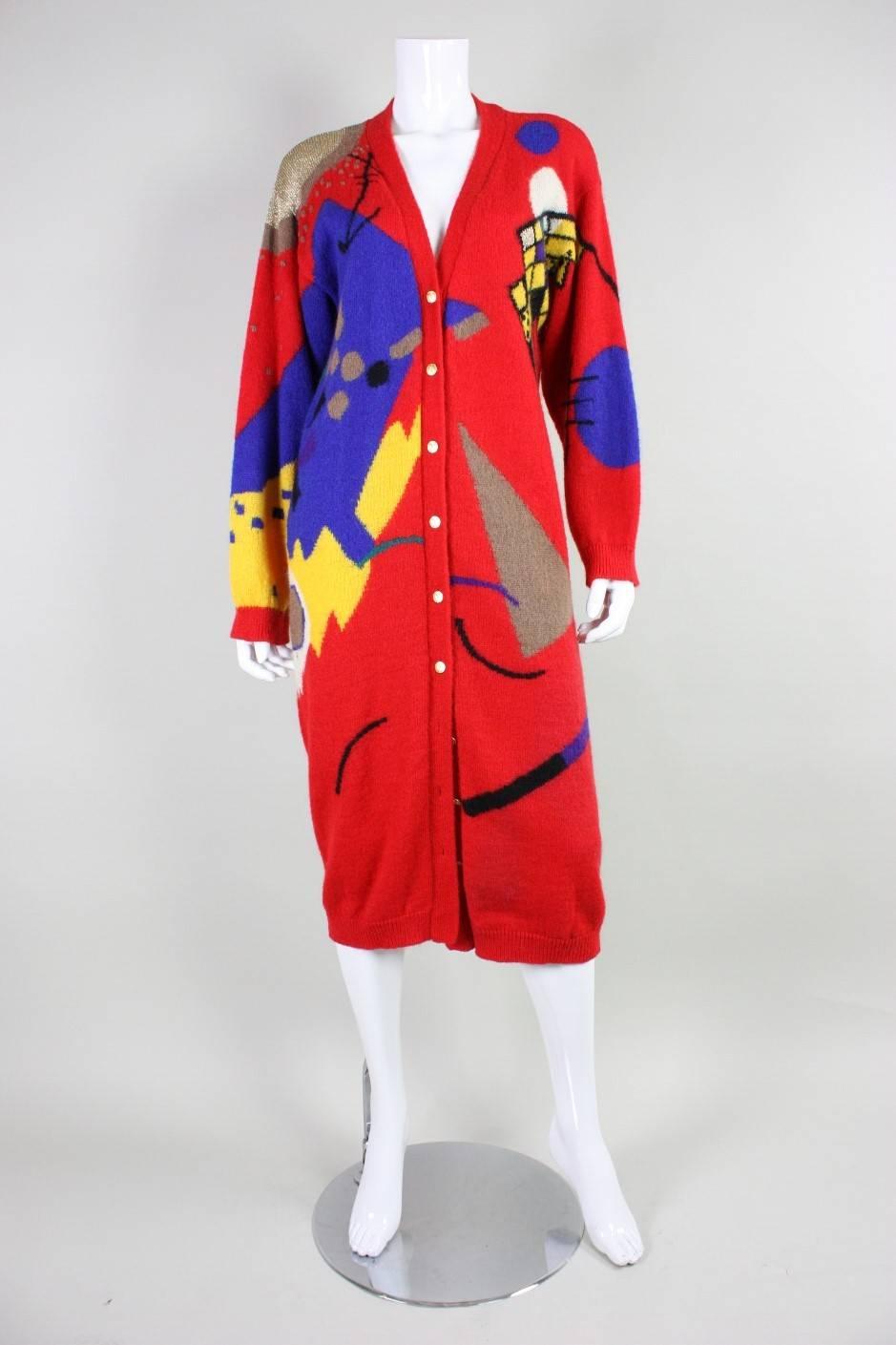 Vintage cardigan from Hanae Mori dates to the 1980's and is made of red acrylic and wool.  It features a bold graphic abstract print in bright colors.  Cardigan features ribbed trim along edges.  Center front gold-toned button closures.  Unlined.