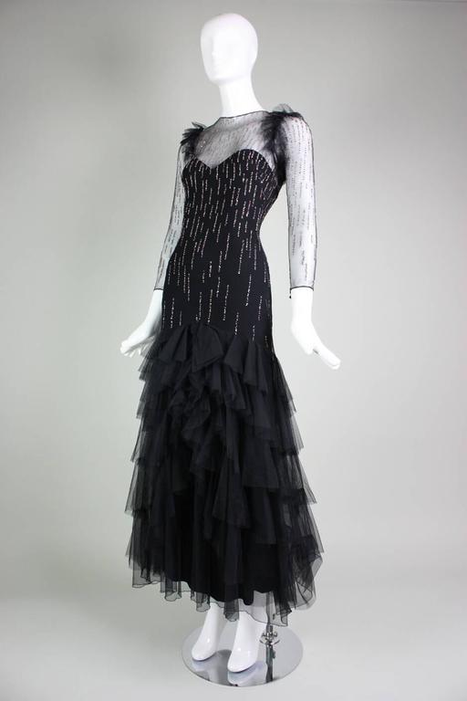 Vintage gown from Loris Azzaro dates to the 1970's and is made of black netting with glitter dots in a stripe pattern.  Tiered ruffle skirt with bow at center front.  Gown is lined except for neckline and sleeves. Center back zippered closure with