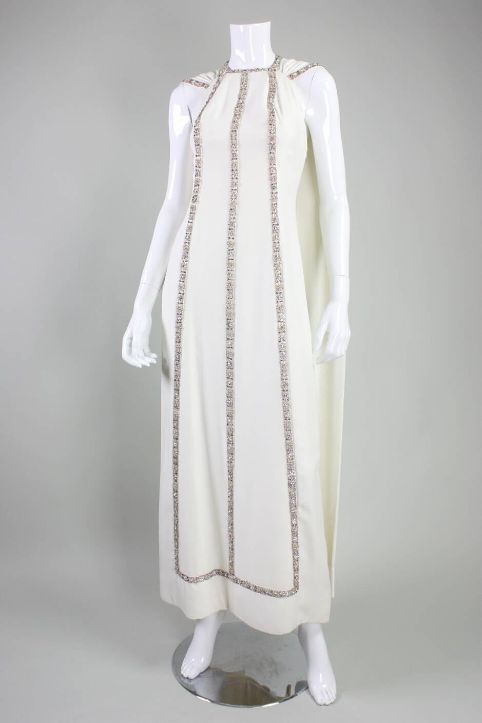 Vintage gown and cape from Italian couture house Gattinoni dates to the mid 1960’s.  Gown is made of cream four ply silk and is adorned with exquisite trim made of woven raffia, rhinestones, faux pearls and beads.  Floor length textured pink cape