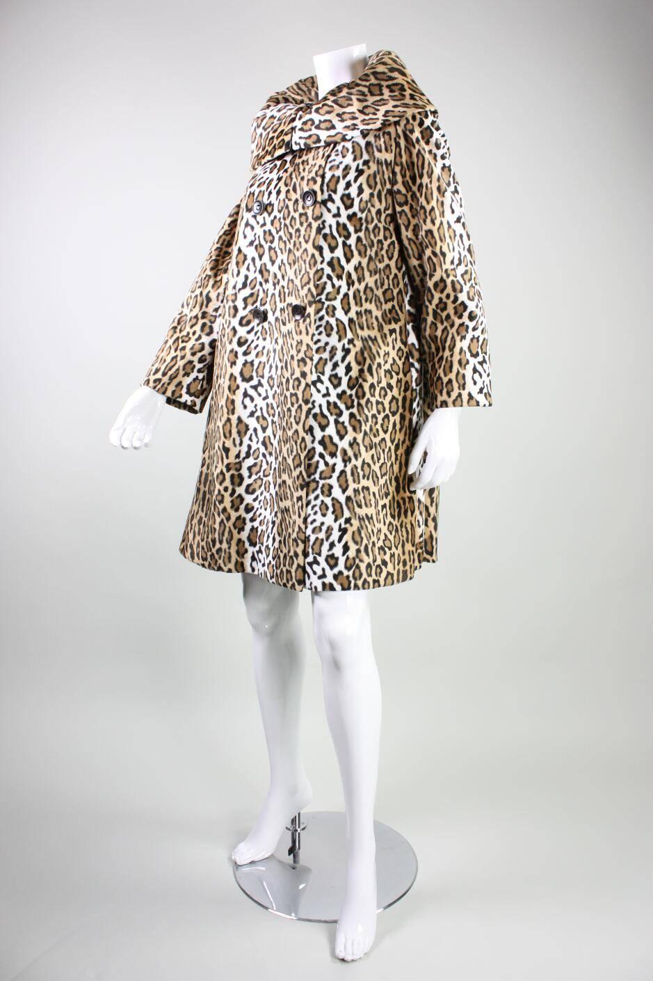 Vintage coat from Moschino likely dates to the 1990's and features a leopard print in neutral tones. Wide portrait collar is shaped with multiple darts. Double-breasted with round buttons that have heart-shaped cutouts. A-line silhouette with