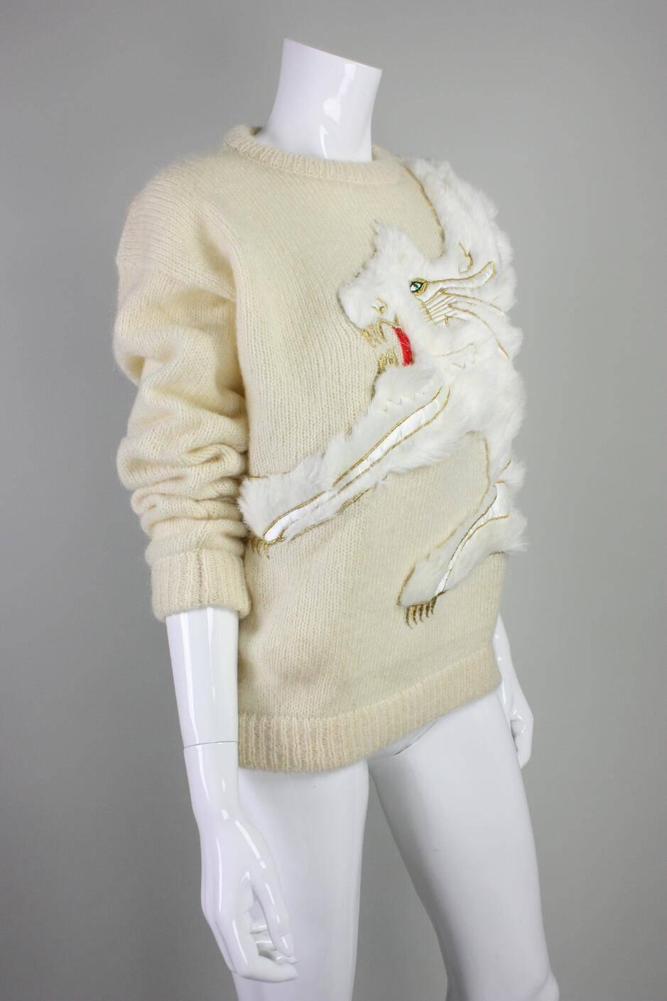 Vintage sweater from Kansai Yamamoto likely dates to the 1980's and is made of a wool/acrylic blend and features an appliqued creature made of white fur with gold, white and red embroidery.   Ribbed cuffs, collar, and waistband.  Unlined with no