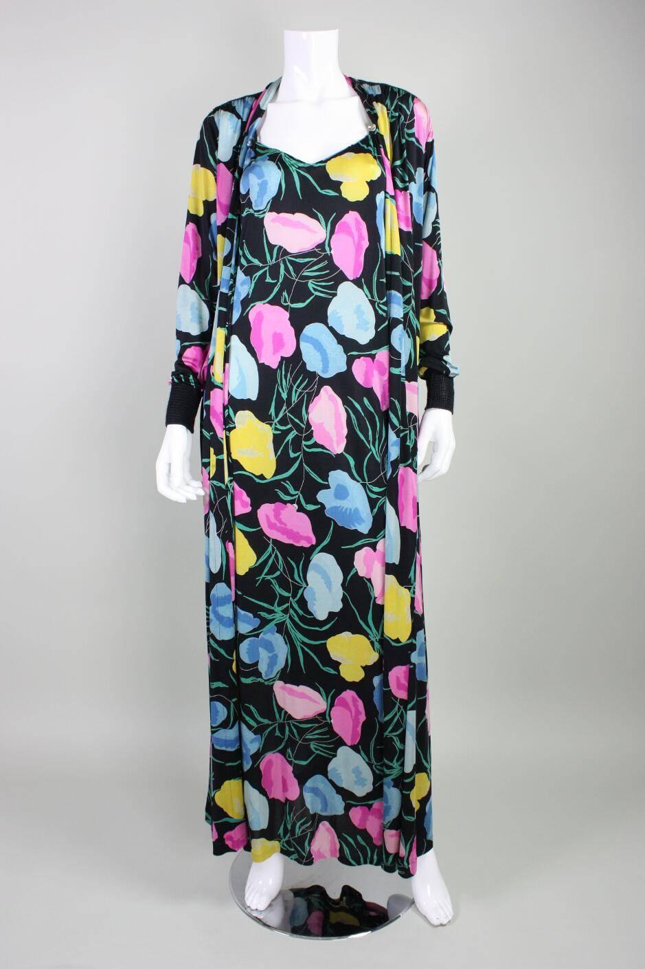 Vintage gown and jacket ensemble from Missoni dates to the 1970's and is made of silk jersey with an abstract floral print.  Sheath gown has front and back V neck with black woven spaghetti straps and a center back slit.  Ankle length jacket has