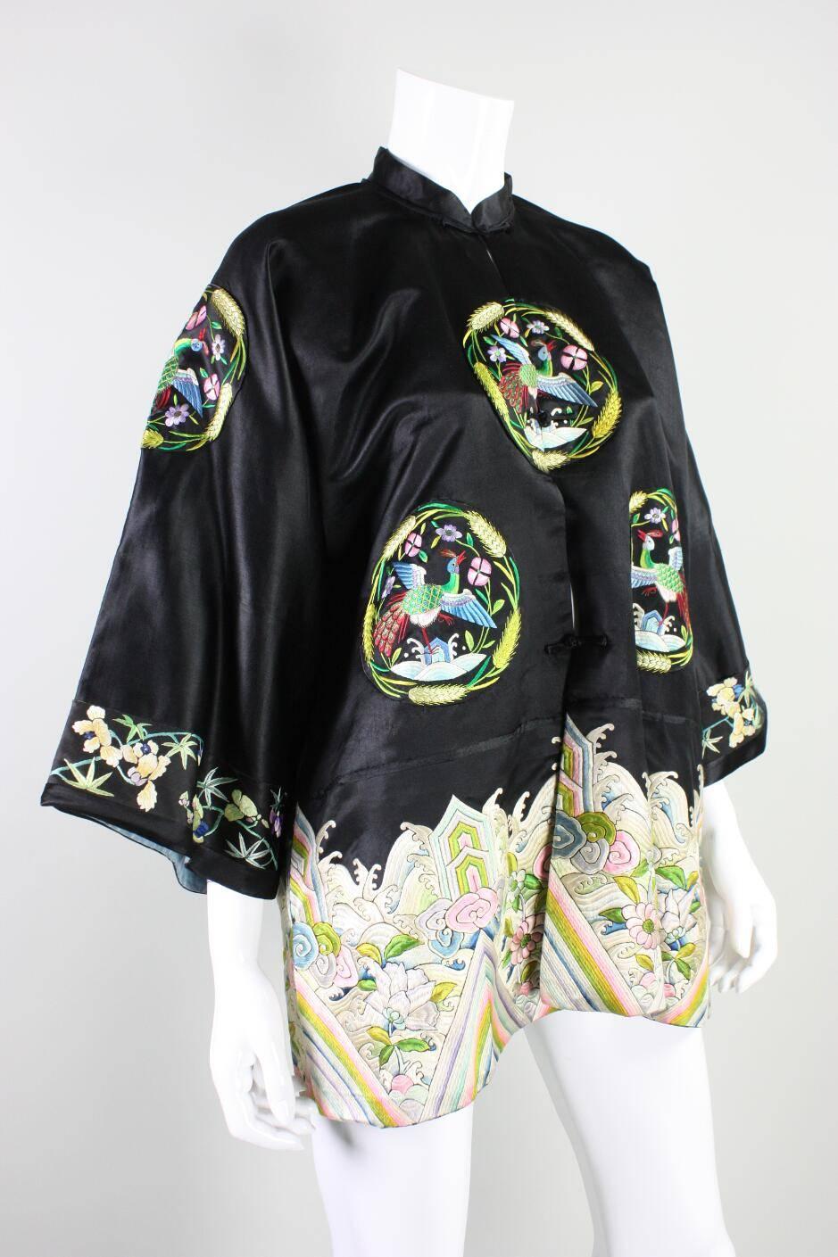 Vintage Chinese jacket likely dates to the 1930's and is made of black silk with multi-colored figural embroidery.  Jacket features eight bird medallion embroideries as well as large heavily embroidered floral pattern at the hem.  Center front frog