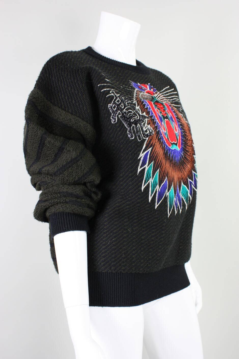 Vintage sweater from Kansai Yamamoto dates to the 1980's and is made of black and brown wool.  It features a brightly colored fierce creature on the bust that is flanked by Japanese characters.  Round neck.  Long sleeves.  Unlined. No
