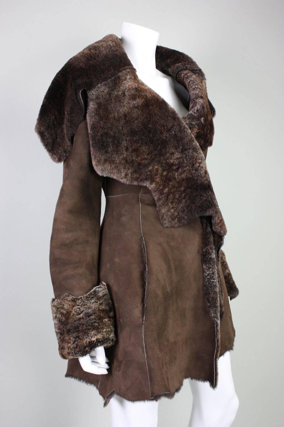 Vintage coat from Roberto Cavalli likely dates to the 1980's and is made of chocolate brown suede and is completely lined with brown shearling. Coat is asymmetrical in construction, but not aggressively so.  Over-sized cuffs and collar. Side-seam