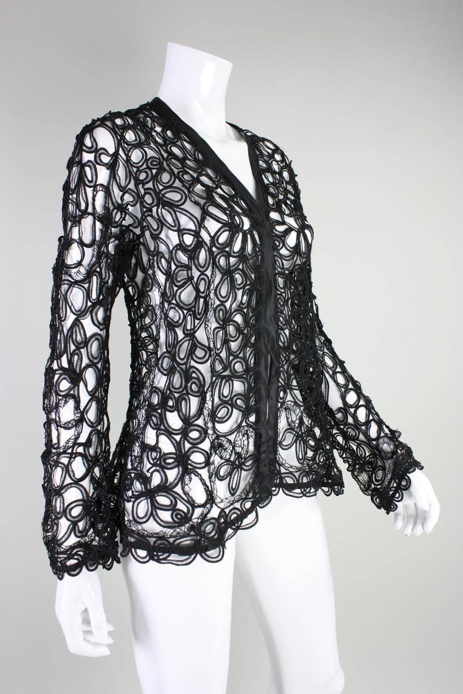 Vintage jacket dates to the Edwardian era during the early part of the 20th century.  It is made of cotton tape lace that is hand tacked together in a swirling and rhythmic pattern.  Black silk taffeta edging. Unlined.  Single hook and eye closure