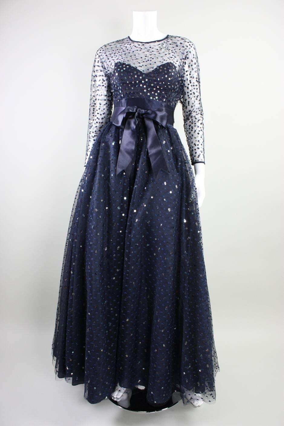 Vintage gown from Victor Costa retailed at Neiman Marcus and is made of navy blue dotted and sequined tulle.  Full skirt with lining and tulle underneath.  Fitted bodice has attached satin waistband.  Center back zipper.

Measurements-

Bust: