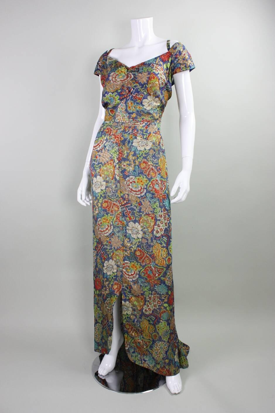 Vintage gown and bolero from I. Magnin date to the 1930's and are made of a blue fabric with gold lame weave and multicolor floral print.  Gown has front and back v neck.  Both pieces are shaped by darts.  Bodice of gown is lined, skirt is unlined. 