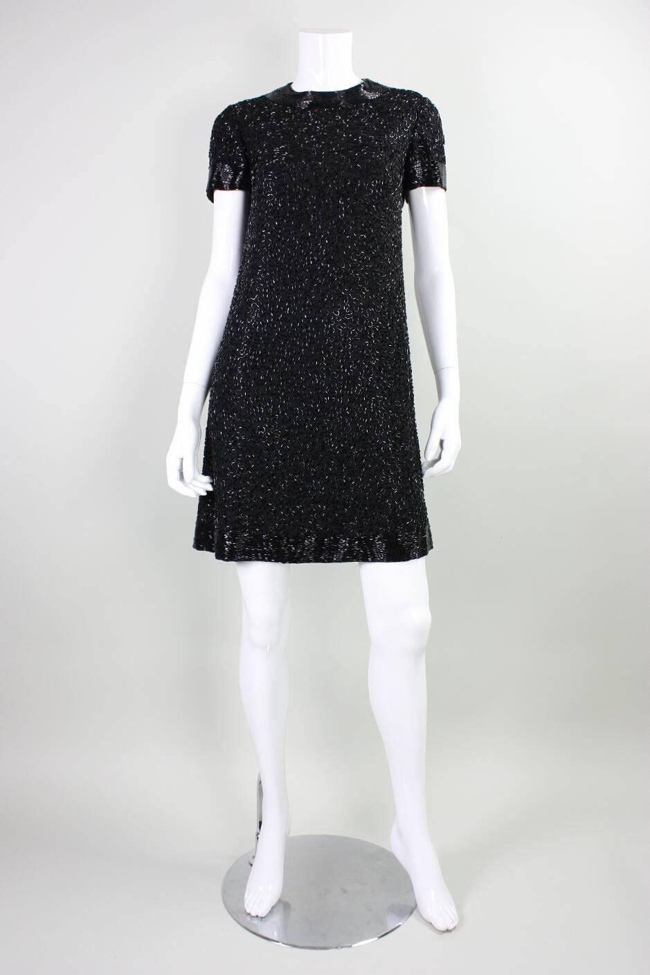 Vintage cocktail dress by Larrry Aldrich dates to the 1960's and retailed at Doris Scott.  It made of black crepe that is adorned with black bugle beads in a squiggle pattern throughout.  Round neck and short sleeves.  Center back zipper.  Fully