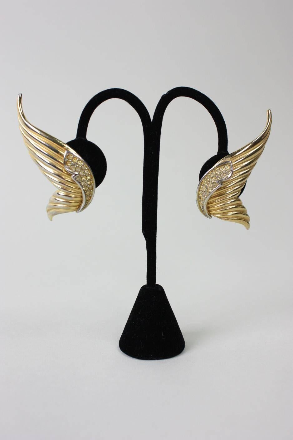 Vintage earrings from Butler & Wilson likely date to the 1980's and are made of gold-toned metal in the shape of wings.  Yellow rhinestone accents at inner ear.  Clip backs. Earrings are stamped B&W.

Measurements-

Length: 2 1/4