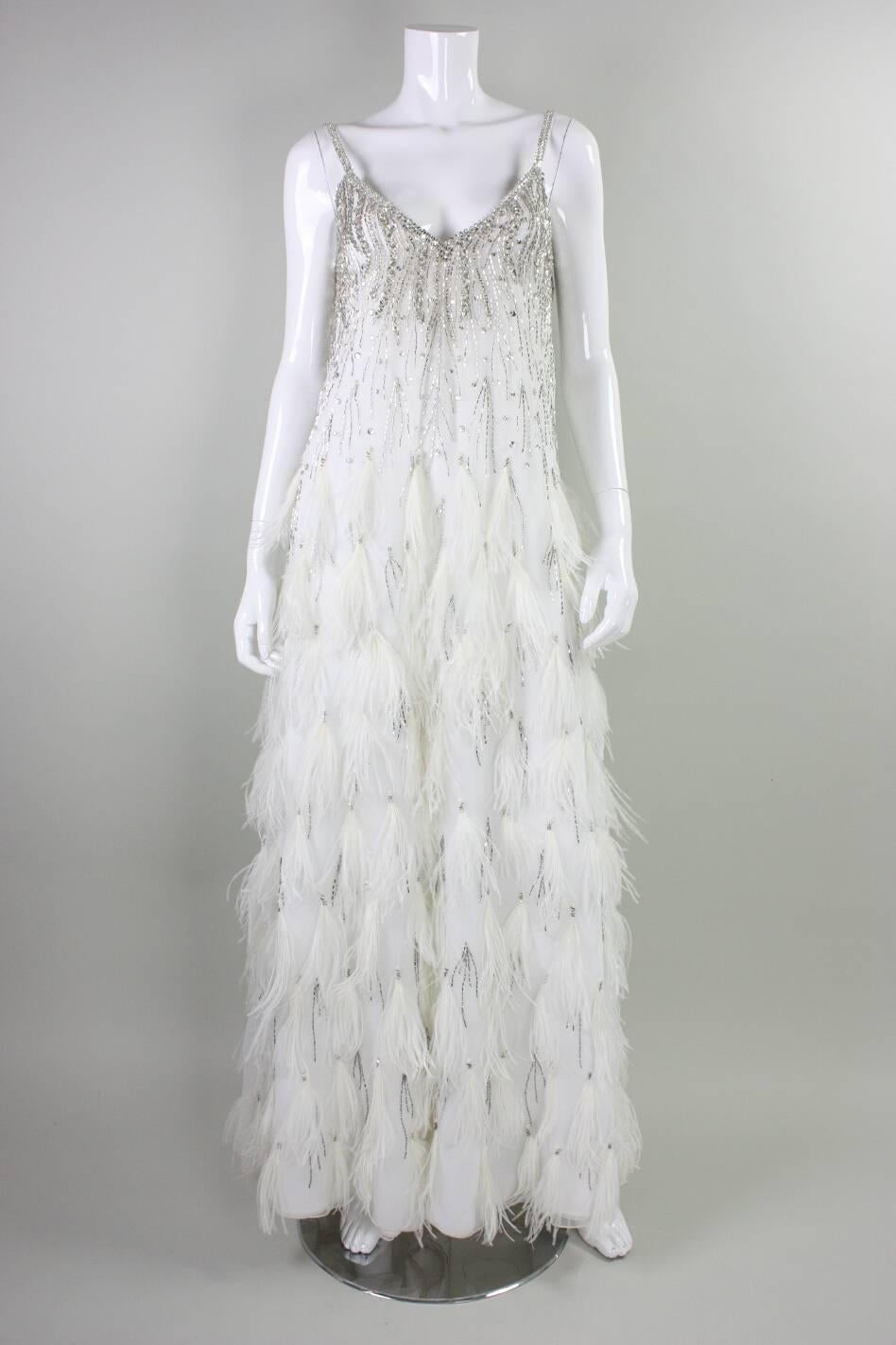Vintage gown from Ruben Panis dates to the 1980's and is made of seven layers of white chiffon and features beadwork throughout and feathers in tiers throughout the entire skirt.  

Measurements-

Bust: 30-36