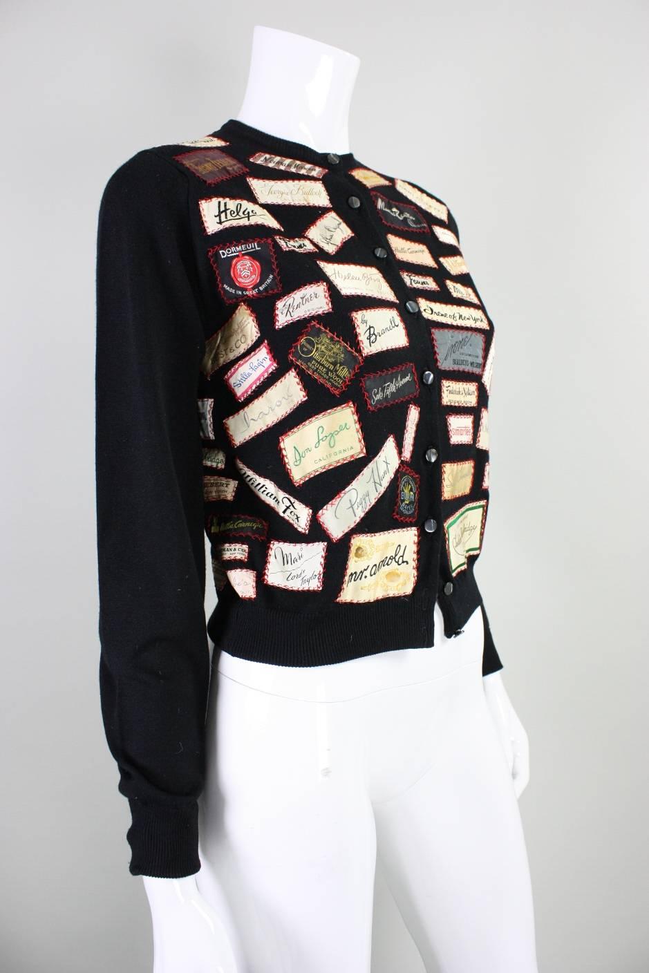 Vintage sweater appears to date to the 1960's.  Cardigan feels to be made of a tightly-woven black acrylic knit and is appliqued with various labels of stores and designers. Applique is hand done in red thread with a decorative stitch.  Cardigan is