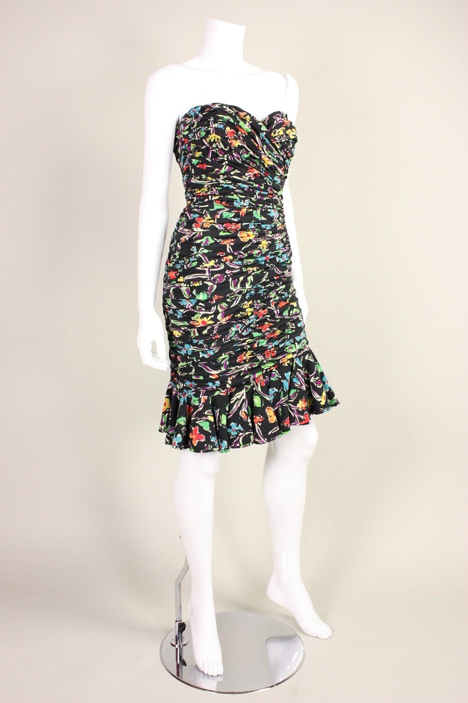 Ungaro cocktail dress dates to the 1980's and is made of printed black silk that is fully ruched.  Asymmetrical skirt has flounce hem.  Side zipper.  Fully lined.

Labeled a vintage size 10, but we estimate it to be a modern size
