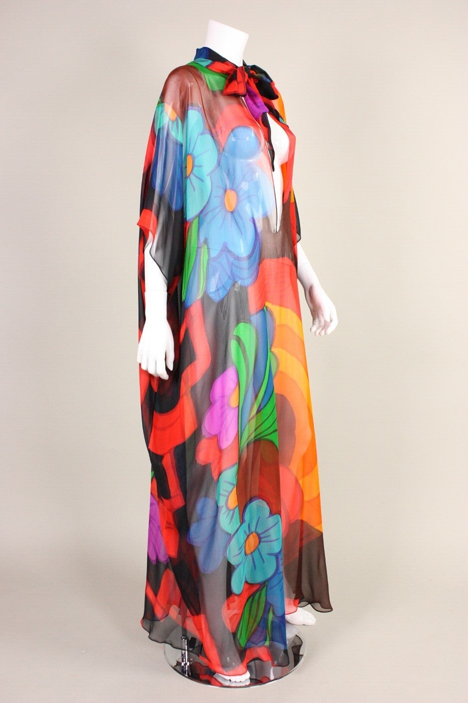1970's caftan with bold psychedelic floral print looks to be hand-painted on silk chiffon.  It has a mock neck with long ties and a center front large keyhole opening that extends nearly to the navel.  Center front hook and eye closure at neckline. 