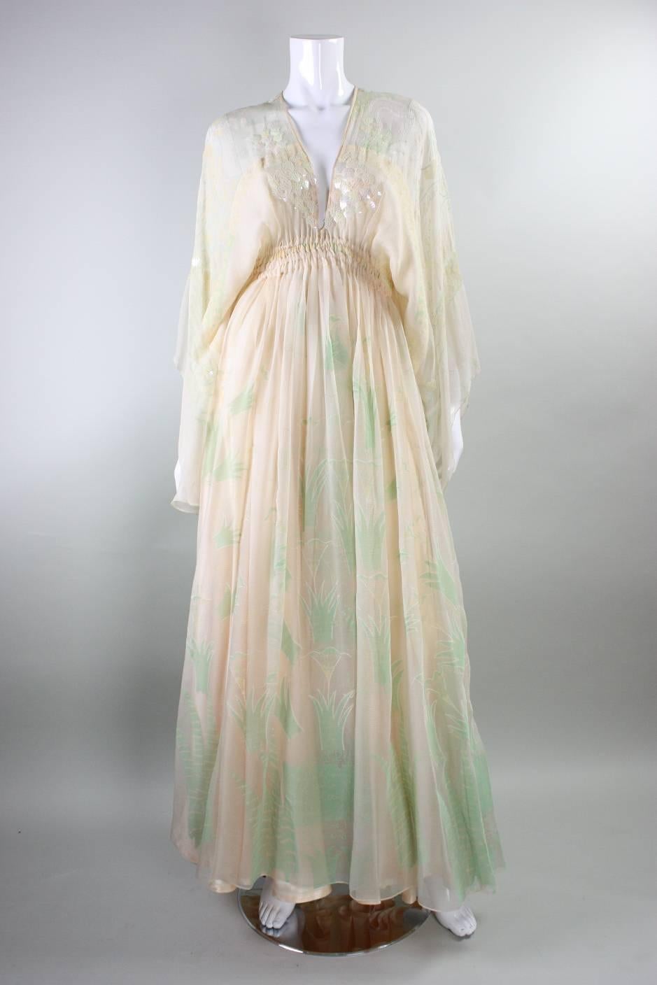 Vintage and iconic Zandra Rhodes Field of Lilies gown dates to the 1970's.  It is made of pale peach chiffon that has silkscreened images and wording throughout.  Leaf-shaped iridescent paillettes highlight the bust.  Elasticized waist is tightly