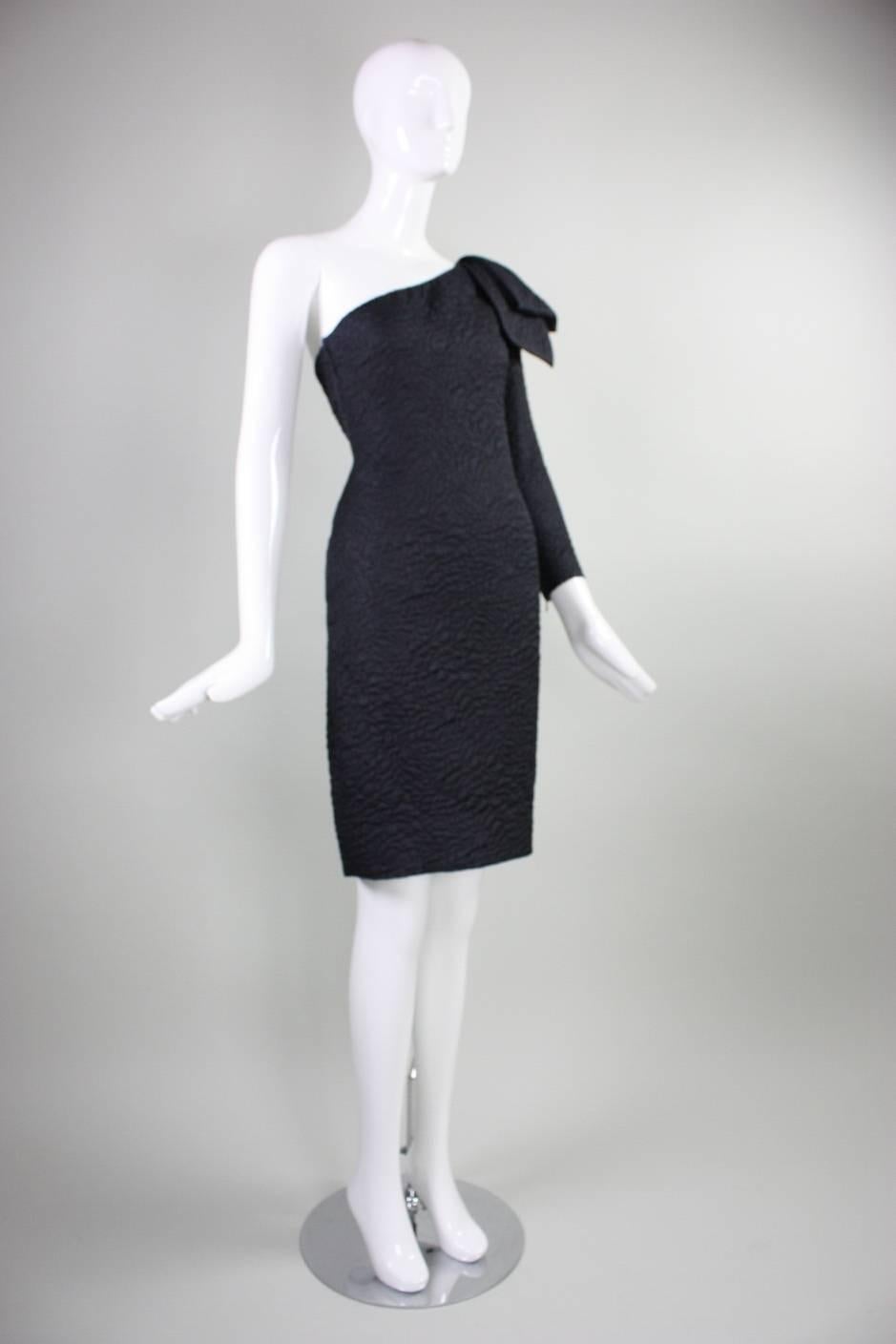 Vintage cocktail dress from Yves Saint Laurent dates to the 1980's and is made of a textured wool/silk blend.  Dress features a dramatic one-shouldered design with an oversized bow on the shoulder.  Zipped cuff.  Fully lined.  Side zipper.

Labeled