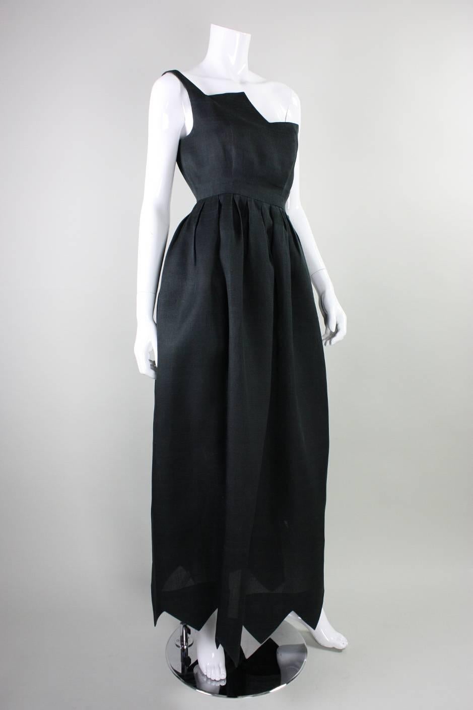 Vintage gown from Christian Dior dates to the 1960's and is made of black textured fabric.  It features a one-shouldered, fitted bodice with an unusual zigzagged detailing.  Full-length skirt is pleated all around waistband with a coordinating