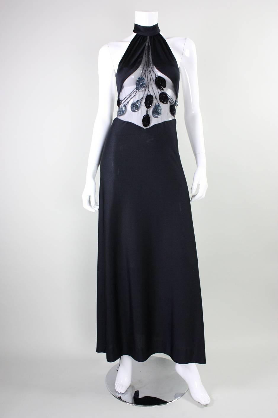 Vintage gown from Loris Azzaro dates to the 1970's and is made of black jersey with a transparent chiffon insert in front and back bodice.  Insert is adorned with black and slate blue sequins and black bugle beads. Halter style neckline. Center back