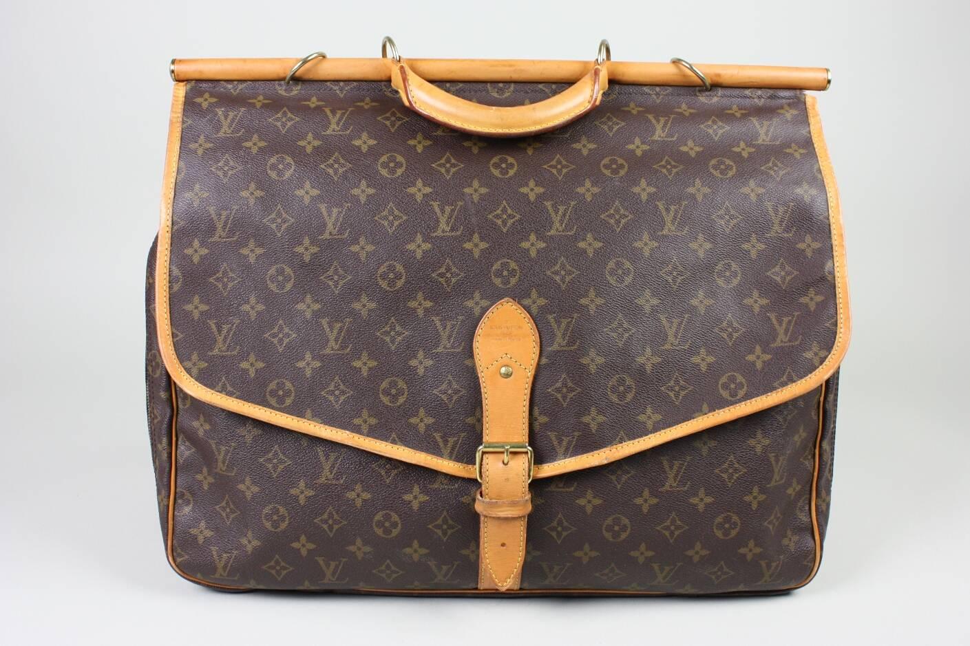 Louis Vuitton Sac Chasse is made of brown monogram coated canvas with tan vachetta leather trim.  It features brass hardware, rolled top handle, a single exterior pocket at front, and a flap pocket at back with three compartments.  Main compartment