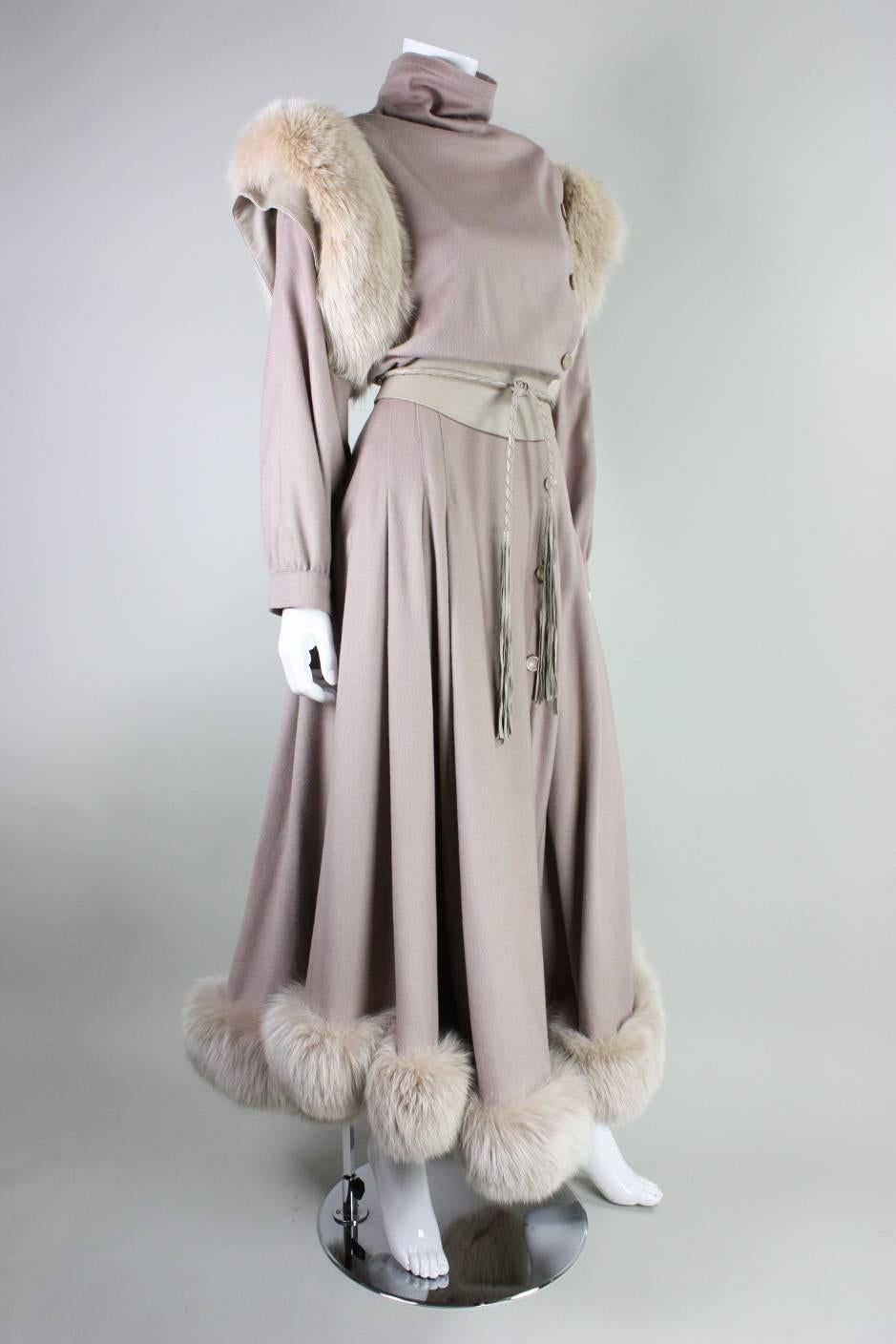 Vintage dress from Bernard Perris dates to the 1980's and is made of taupe wool with cream fox fur trim around shoulders and at hem.  Asymmetrical button closure.  Full skirt.  Lightly padded shoulders.  Detached leather sash with braided