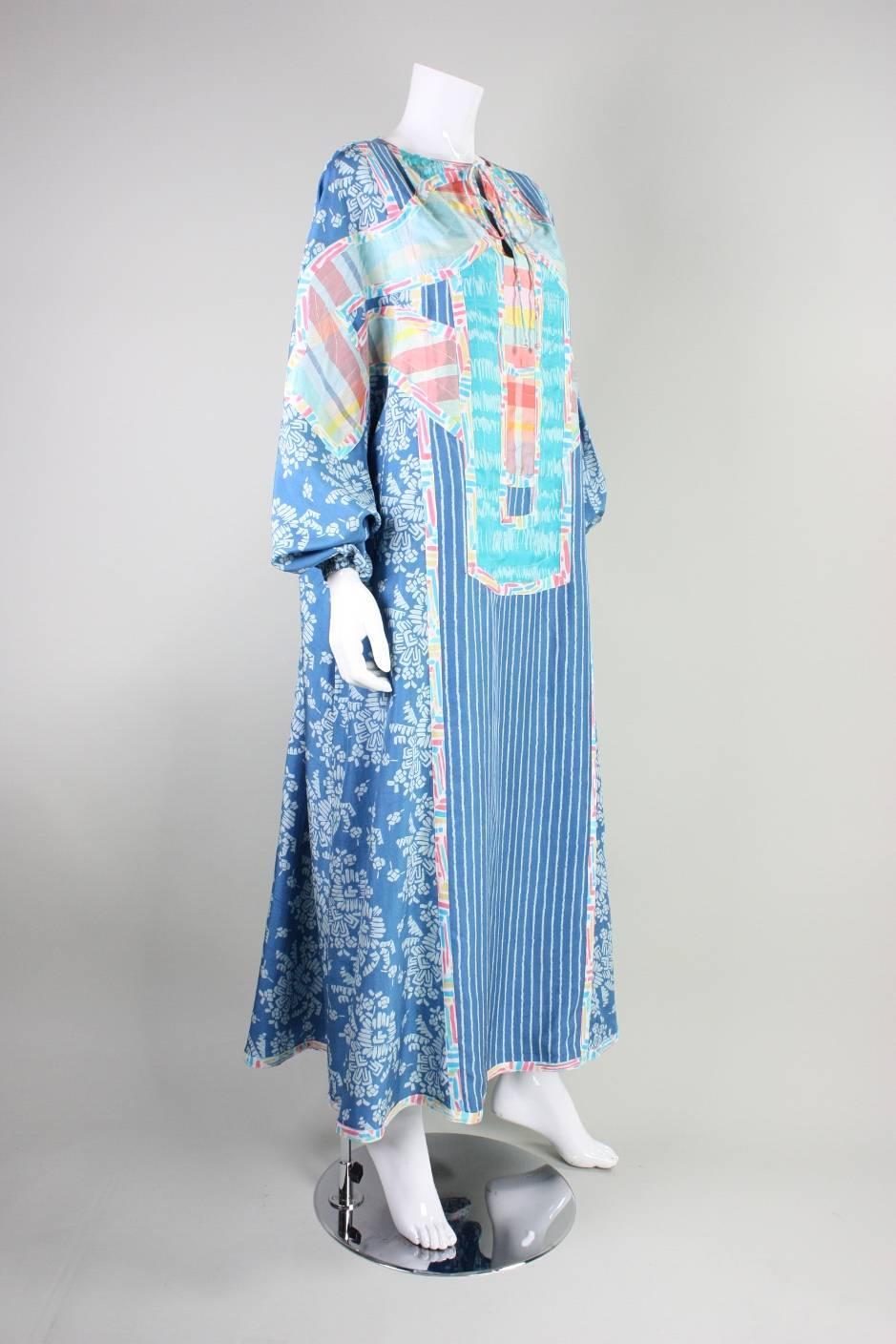 Vintage caftan from Koos Van Den Akker dates to the 1980's and is made of mixed patterns and colors of silk fabrics that are artfully pieced together.  Round neckline has center front slit and ties. Batwing sleeves have elasticized cuffs. Hip
