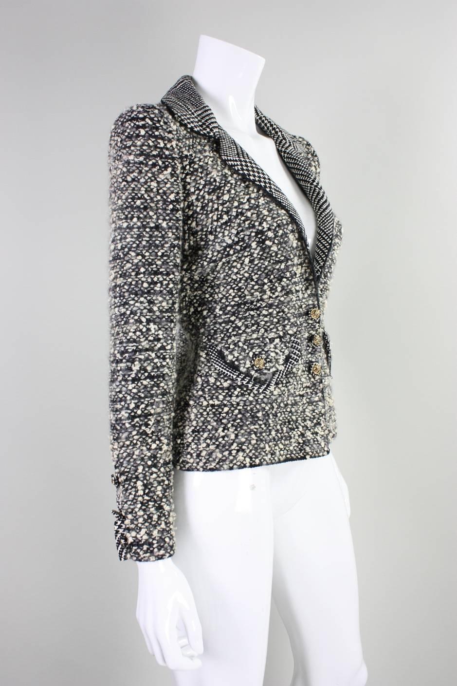 Vintage jacket from Adolfo dates to the 1980's and is made of a black, white, and gray wool boucle.  It features a notch lapel with silk that is printed in a houndstooth pattern.  Matching fabric trims the buttons, faux pockets, and faux opening at