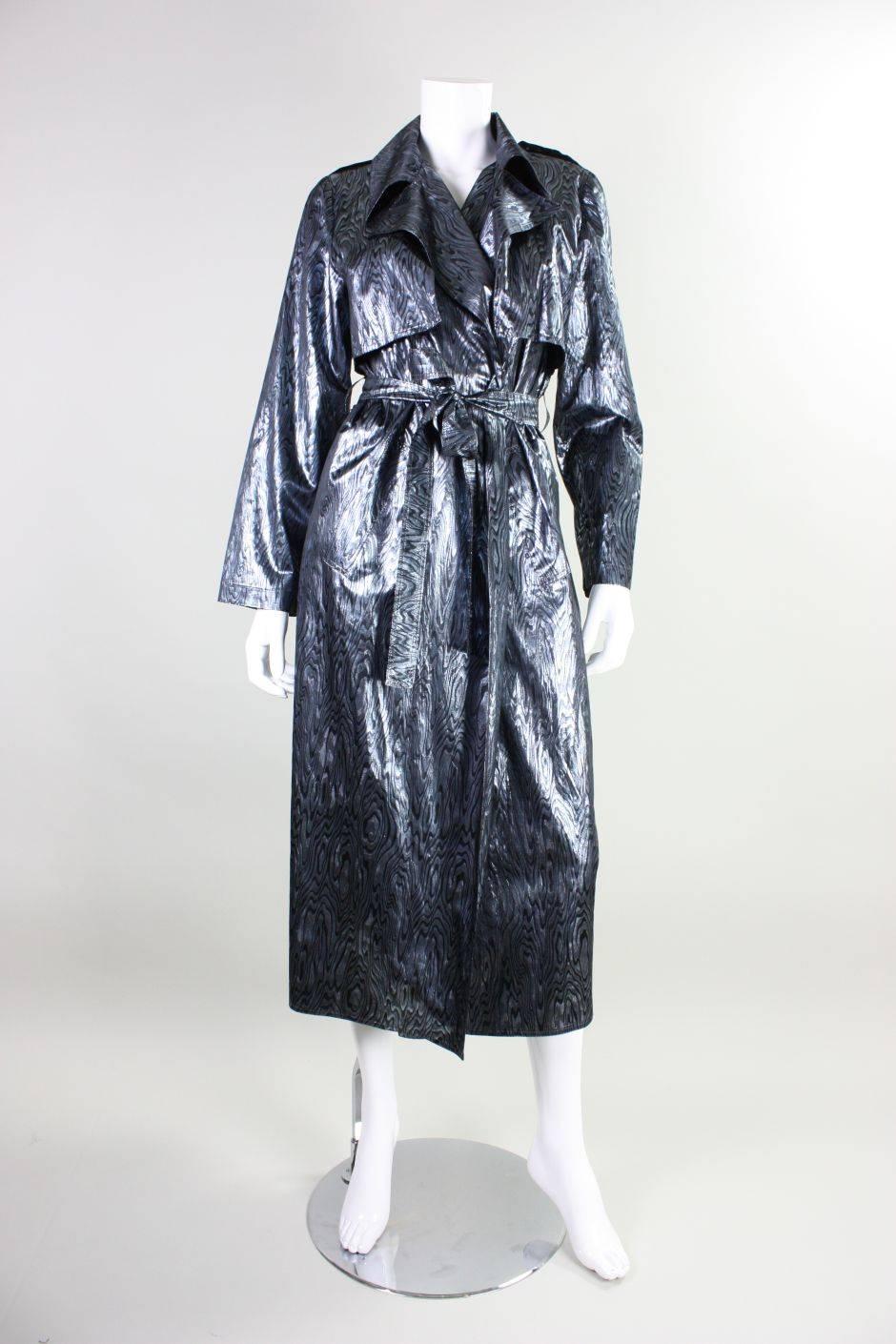 Vintage trench coat by Vicky Tiel retailed at Bergdorf Goodman and dates to the 1980's through 1990's.  It is made of silver and black lame fabric with a woodgrain pattern.  Slanted pockets at hip. Center back vent. Unlined. No closures outside of a