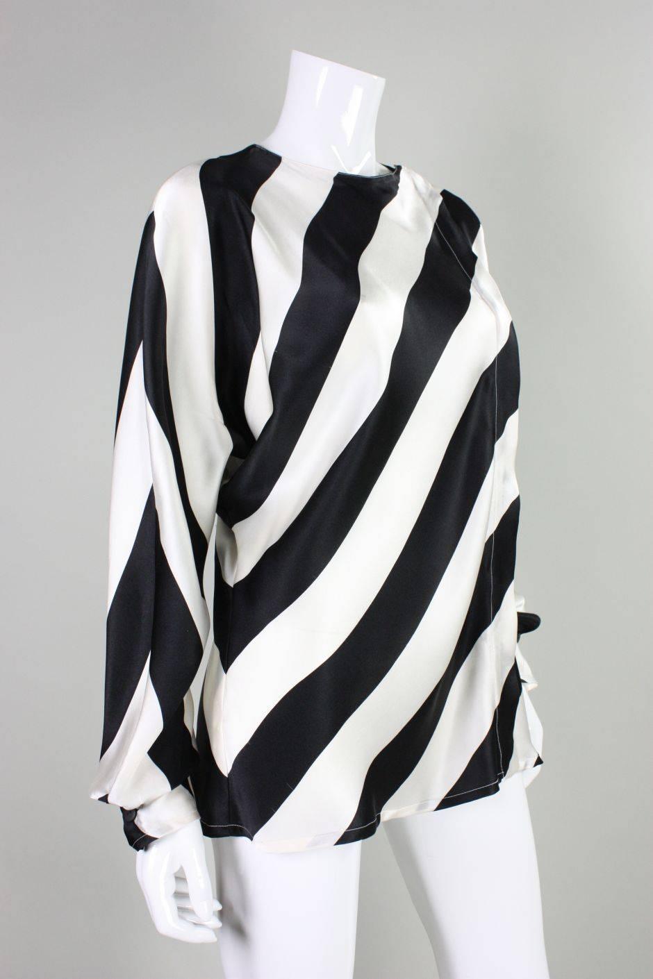 This blouse from Krizia dates to the 1980's and is made of silk charmeuse with a black and white diagonal print.  Dolman sleeves with buttoned cuffs.  Off-center lapped button front closures. Unlined.