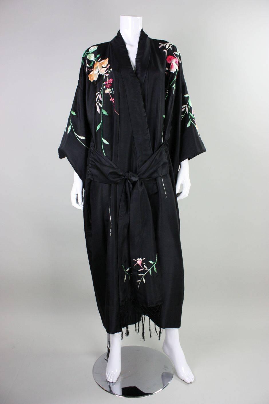 Vintage kimono robe dates to the 1920's and is made of black silk that features polychromatic padded hand-embroidery with a floral motif.  Fully lined. Waist ties are attached at approximately the side hips.

Measurements-
Bust: 50