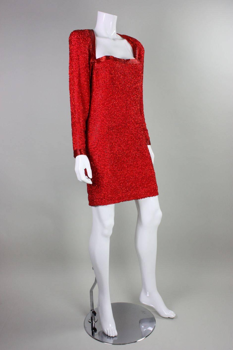 Vintage party dress from Stephen Yurich dates to the 1980's and is made of red silk that is embellished allover with red bugle beads in an abstract squiggle pattern. Squared neckline.   Long sleeves with zipped cuffs.  Padded shoulders.  Fully