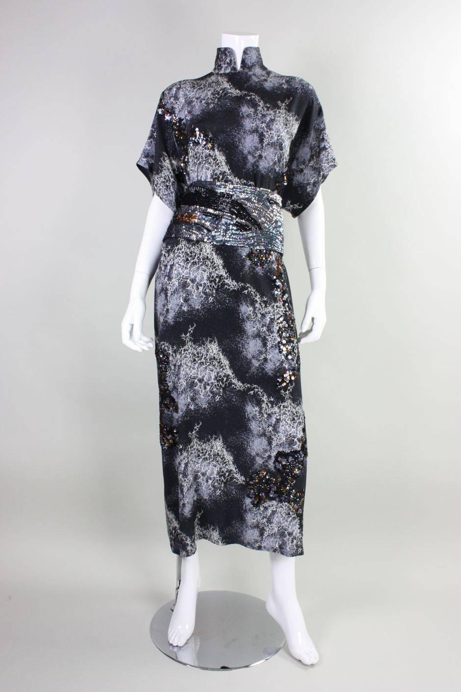 This vintage gown from Hiroko Koshino dates to the 1980's and is made of black silk with an abstract print that is reminiscent of a storm.  Multicolored sequins are hand-sewn in clusters onto the gown and the detached sash is completely covered in