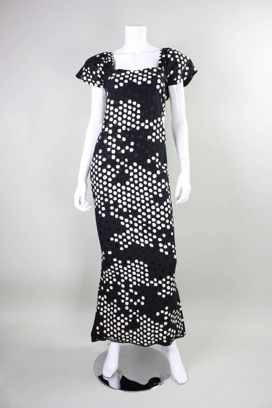 Vintage gown from Andrea Odicini dates to the 1980's and is made of black and white polka-dotted silk.  Squared neckline with gathered short sleeves.  Dramatic open back is accented with large bows.  Fishtail hem.  Fully lined.  Zippered and snap