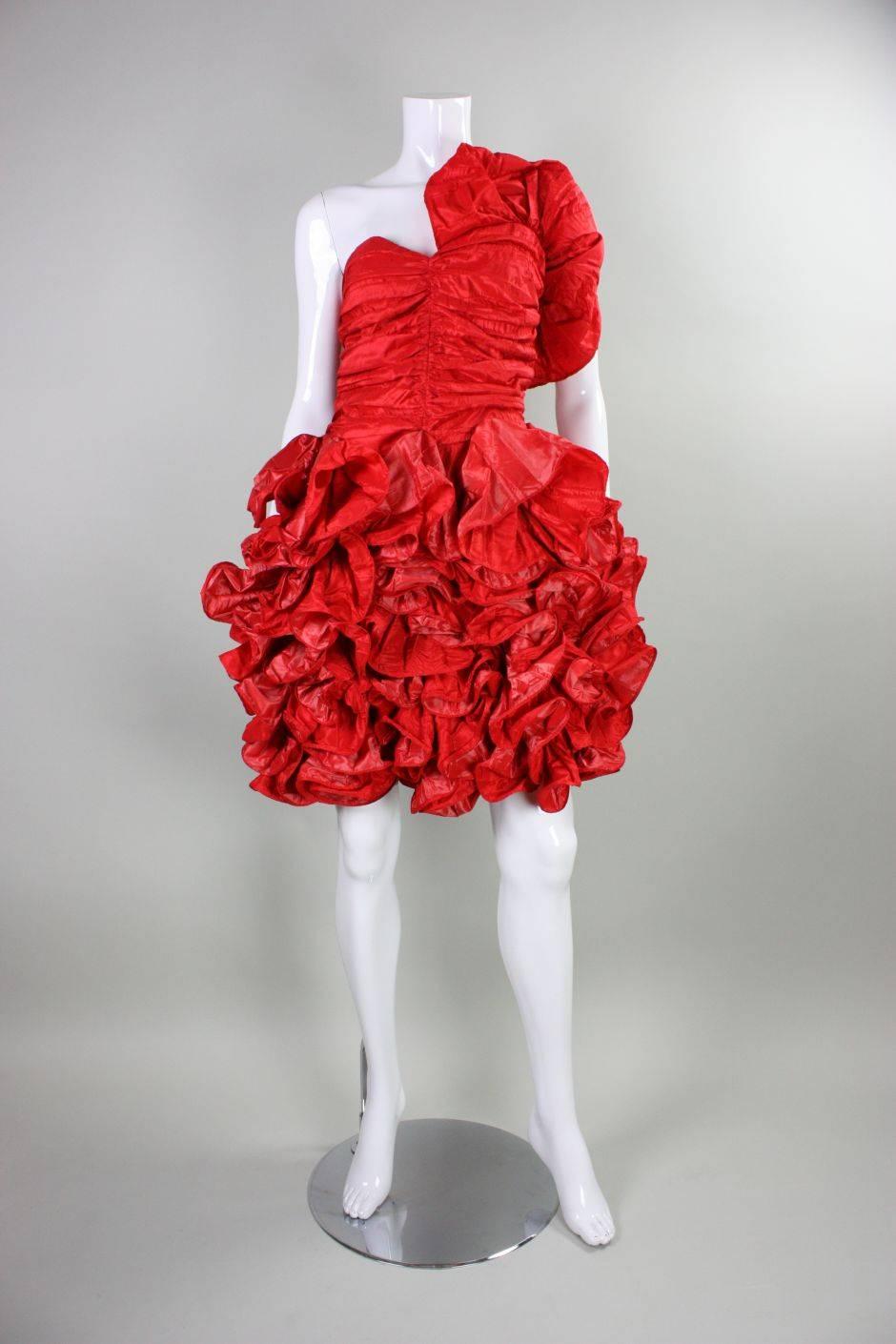 Vintage dress from Christian Dior retailed at Giorgio of Beverly Hills and dates to the 1980's.  It is made of red textured taffeta that is gathered at the center front and side seams of the bodice.  One shoulder with large dramatic ruffle.  Full