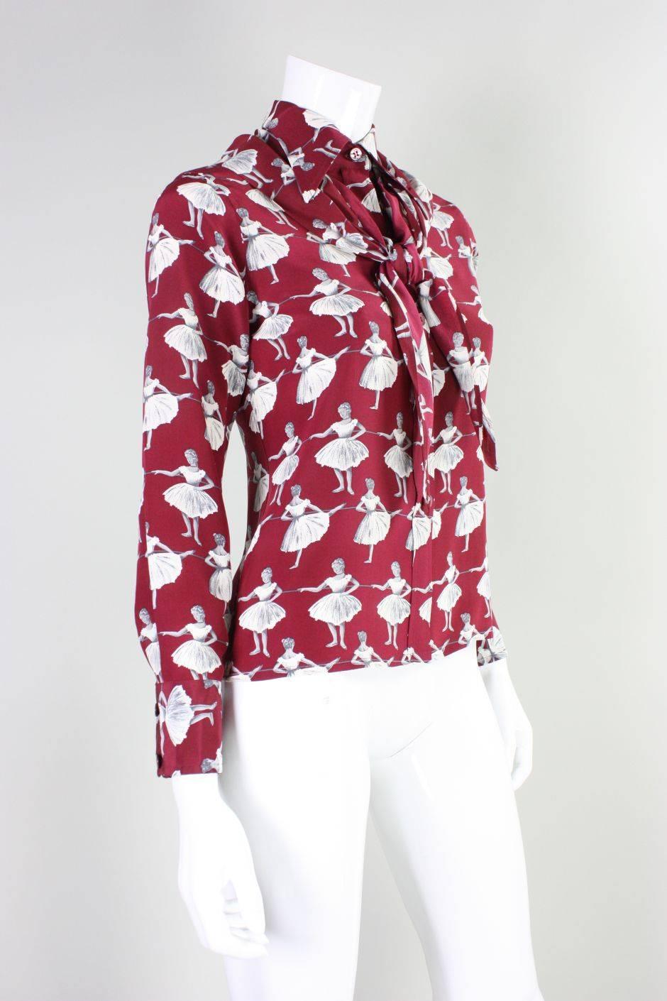 Vintage blouse from Valentino dates to the 1970's and is made of wine-colored silk that features a gorgeous ballerina print.  Blouse has wide turn-down collar, button front, and a detachable triangular scarf that can be worn in a variety of ways. 