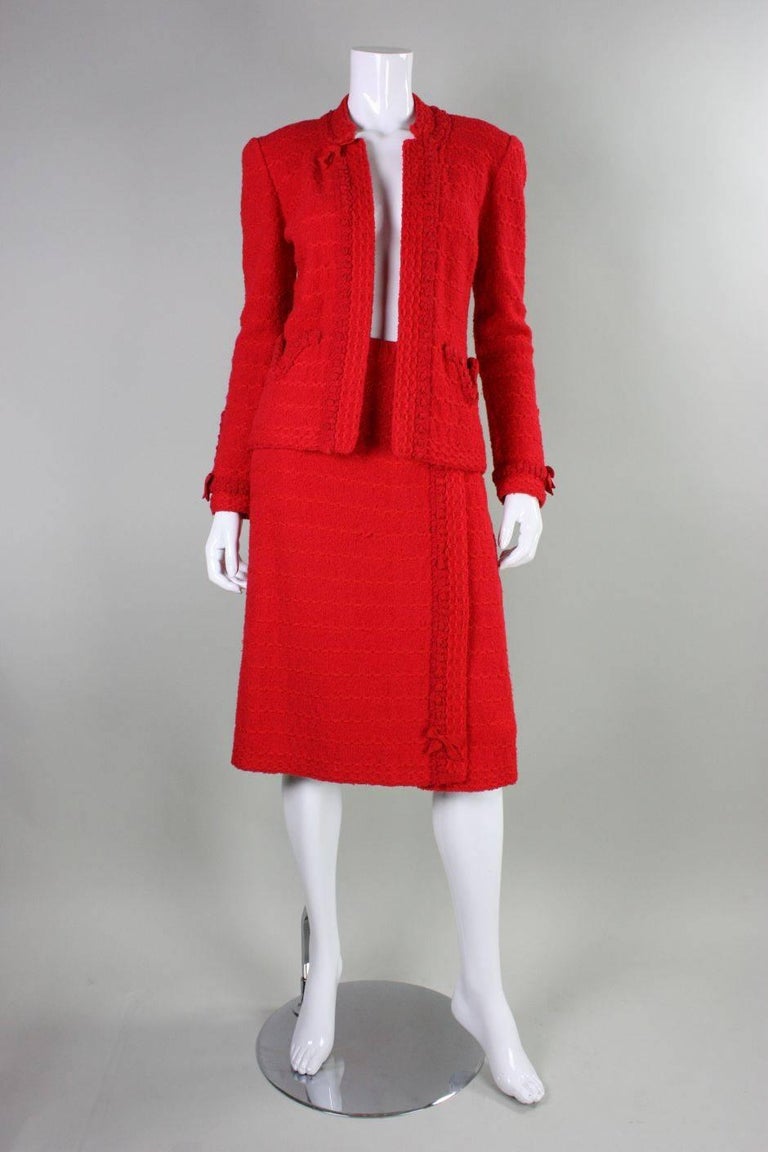 Vintage Adolfo suit ensemble is made of red wool boucle.  Jacket has two front pockets at waist and no closures.  Straight skirt has elasticized waist and no closures.  Both pieces have unusual woven silk ribbon detailing.  Both pieces are