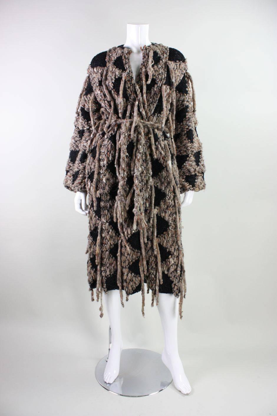 Vintage coat from Beverly Hills designer Gunn-Trigere dates to the 1980's and is made of black and brown chunky wool.  Textured knit has yarn fringe throughout.  Round neck.  Long sleeves.  Unlined.  No closures outside of a detached waist belt.