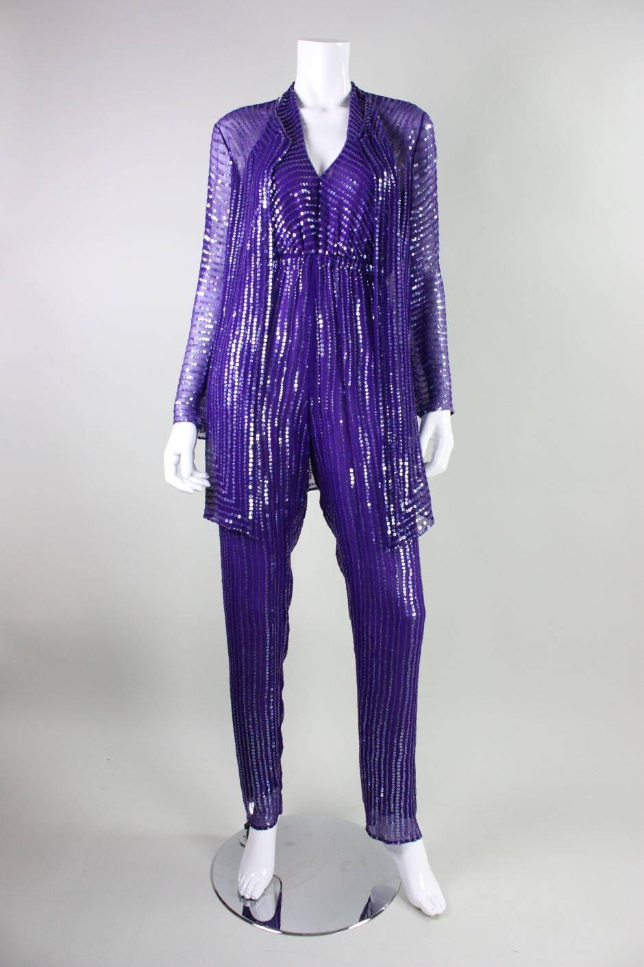 Vintage jumpsuit & jacket ensemble from Halston is made of purple silk chiffon that is covered with  vertical rows of hand-sewn iridescent sequins.  Jumpsuit has plunging halter neckline, open back, elasticized waistband, and center back hook