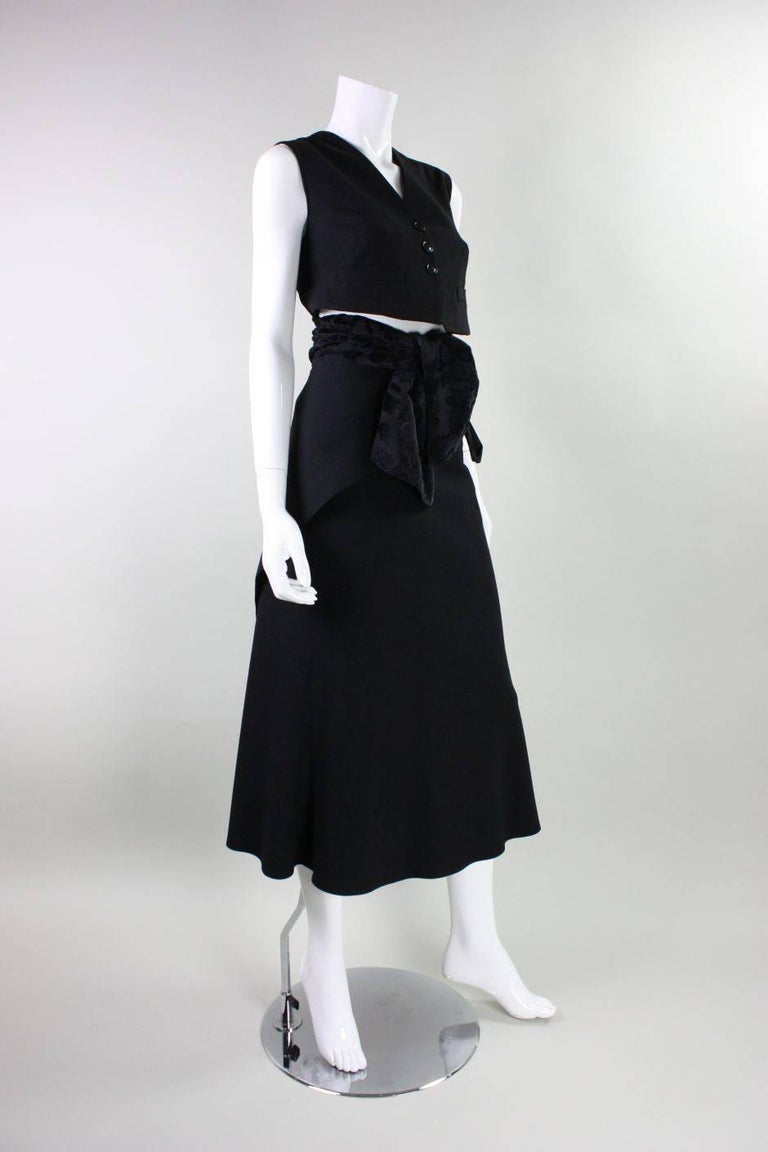 Ann Demeulemeester ensemble consists of a vest and skirt.  Single-breasted vest has a v-neck, center front button closure, and a textured sash that ties around the hips.  Wrap skirt is ankle-length and ties around the waist. Vest is lined. Skirt is