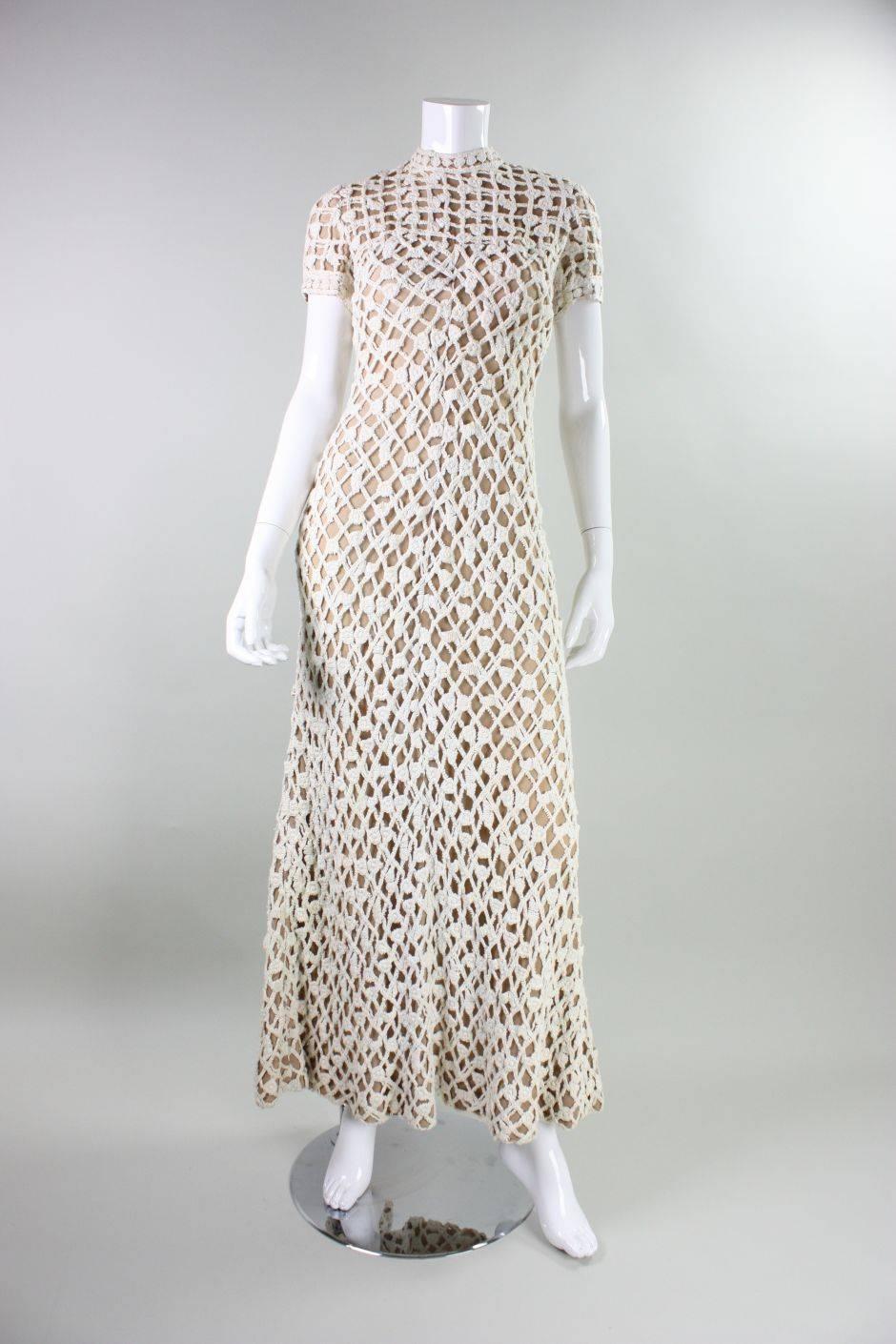 Vintage gown from Werle of Beverly Hills dates to the 1970's and is made of cream-colored crochet that is sewn onto nude netting.  It features a mock neck, short sleeves, and a center back zipper.  Detached shawl measures 20