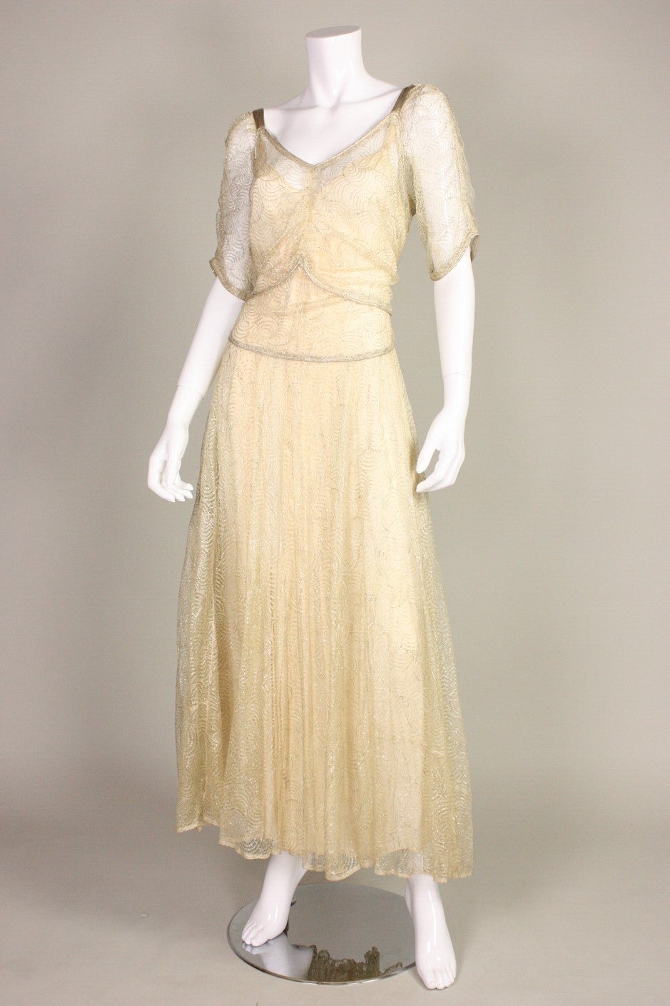 Vintage gown dates to the 1930's and is made of lame lace with an open weave.  Elbow-length sleeves.  Full skirt.  Center back snap closure.  Unlined, but comes with slip.

Measurements-

Bust: 32-36