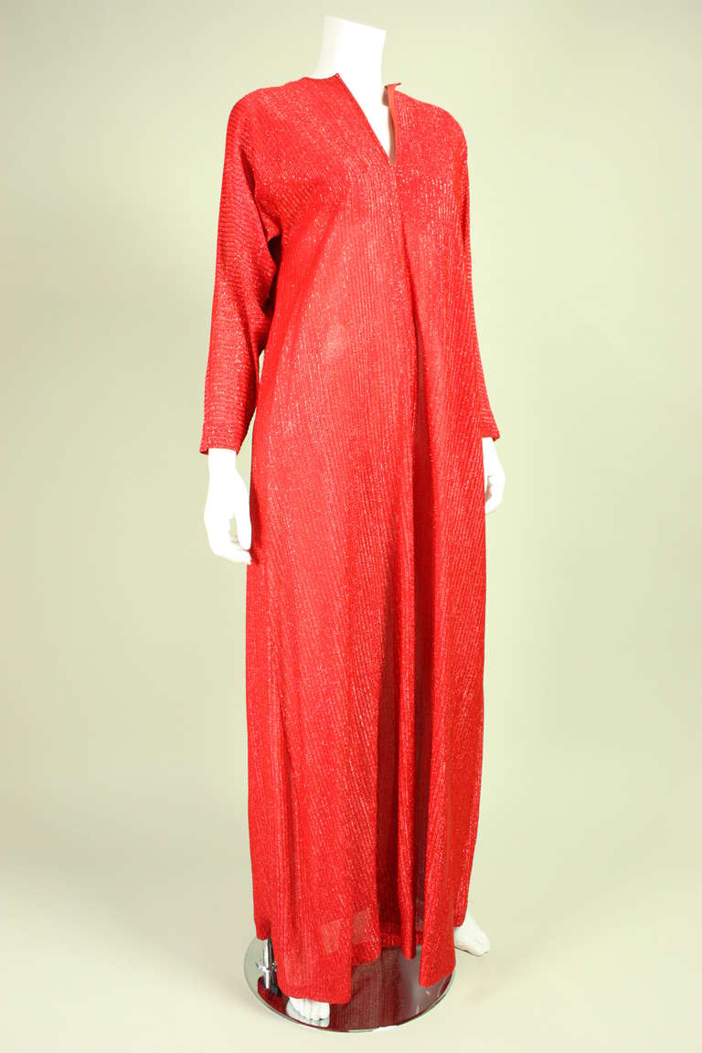 Vintage glam caftan from Halston IV retailed at Saks Fifth Avenue and dates to the 1970's. It is made of metallic red fabric with a self stripe and features a center front slit at the neckline, 7/8-length tapered sleeves, and a center front vent