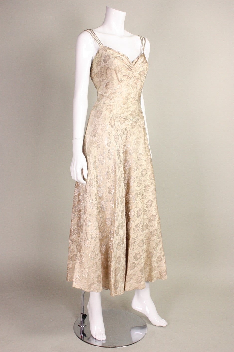 Vintage dress dates to the 1930's and is made of a cream lamé with a light pink hue.  Fabric has a floral & honeycomb pattern.  Front v-neck has gathering at center front bust.  Triple spaghetti straps.  Side snap closure.  Unlined.

No size