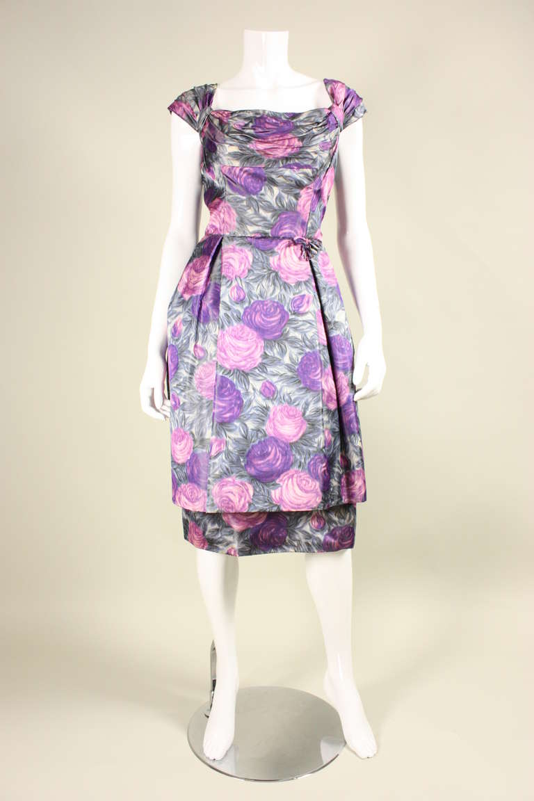 Vintage cocktail dress dates to the 1950's and retailed at Bullock's Westwood.  It is made of beautiful watercolor floral silk taffeta in gray, lavender, and violet.  Ruched at bust, neckline, and sleeves.  Bubble skirt flares over a straight skirt.