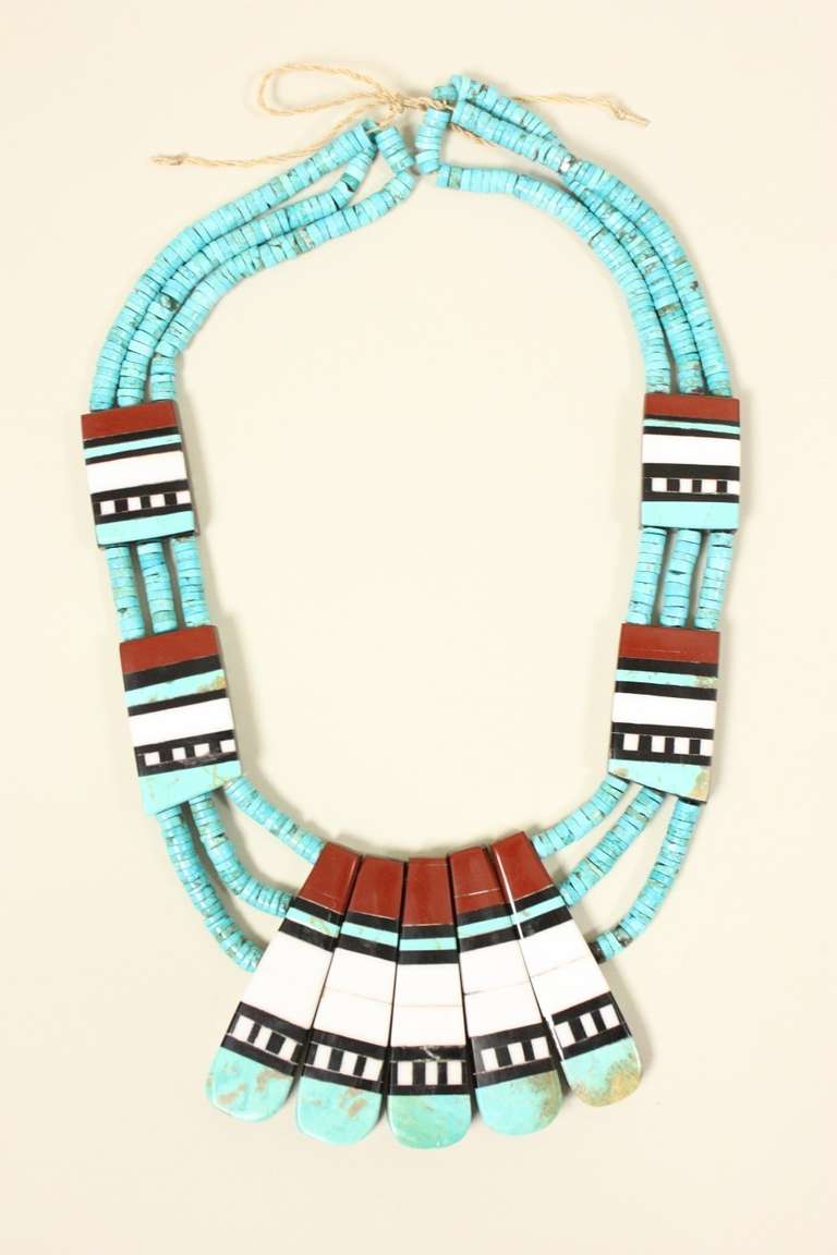 Gorgeous multi-strand necklace accented with inlaid stones and shells is from the Santo Domingo pueblo. Triple strand turquoise heshi has two inlaid plaques on each side at regular intervals between them.  The inlay creates a striking color