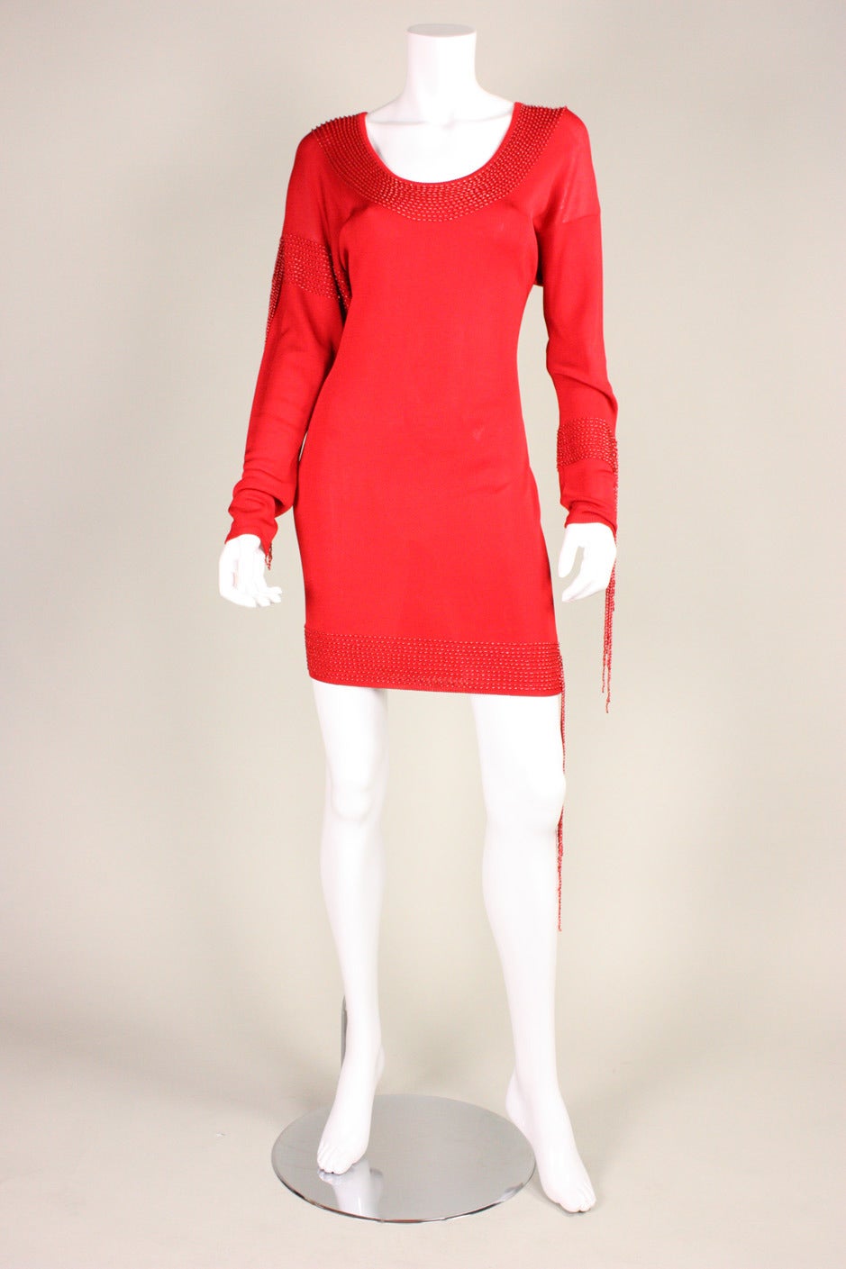 Bodycon dress from Krizia dates to the 1980's and is made of a soft red knit fabric. Beading around neckline, hem, and sleeves.  Strands of beaded fringe cascade down the body.  Unlined.  No closures.  100% Rayon knit.

Labeled size